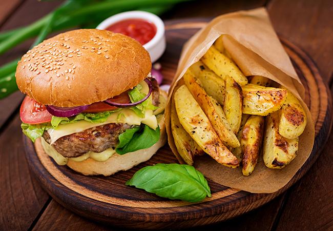 Hamburguesa con patatas y ketchup sobre tabla de madera